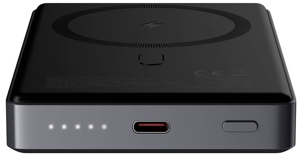 Black portable power bank with wireless charging pad on top, USB-C port and power button on the front, plus four LED charge indicators.