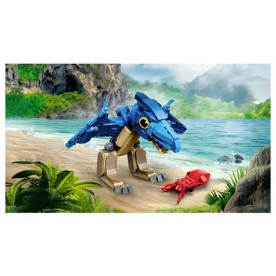 Blue LEGO dinosaur stands on a tropical beach facing a red crab by the shore, with ocean, cliffs, and jungle in the background.