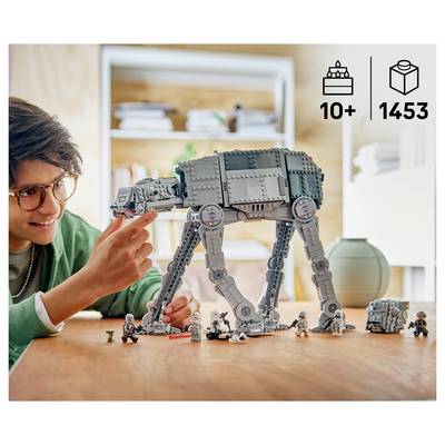 Person assembling a LEGO AT-AT walker on a table, with '10+' and '1453' product icons in the corner.