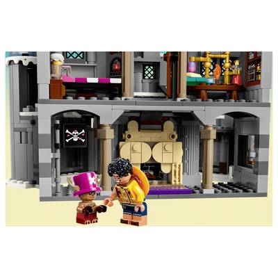 Two LEGO minifigures stand outside a gray castle-like building, one in a pink top hat and the other in an orange jacket, with a skull-and-crossbones sign above the entrance.