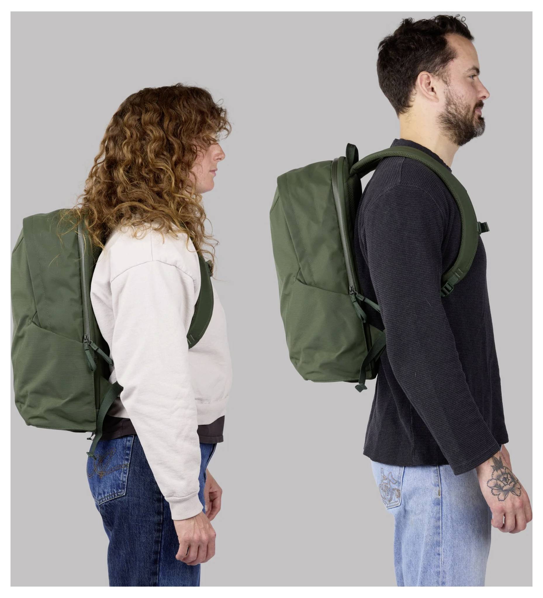 Two people in profile wearing large green backpacks, showing the bags worn on their backs against a plain gray background.