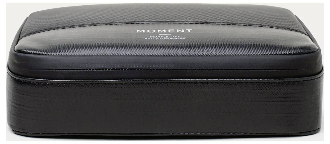 Black zippered hard case with 'MOMENT' logo on top, shown closed against a white background.