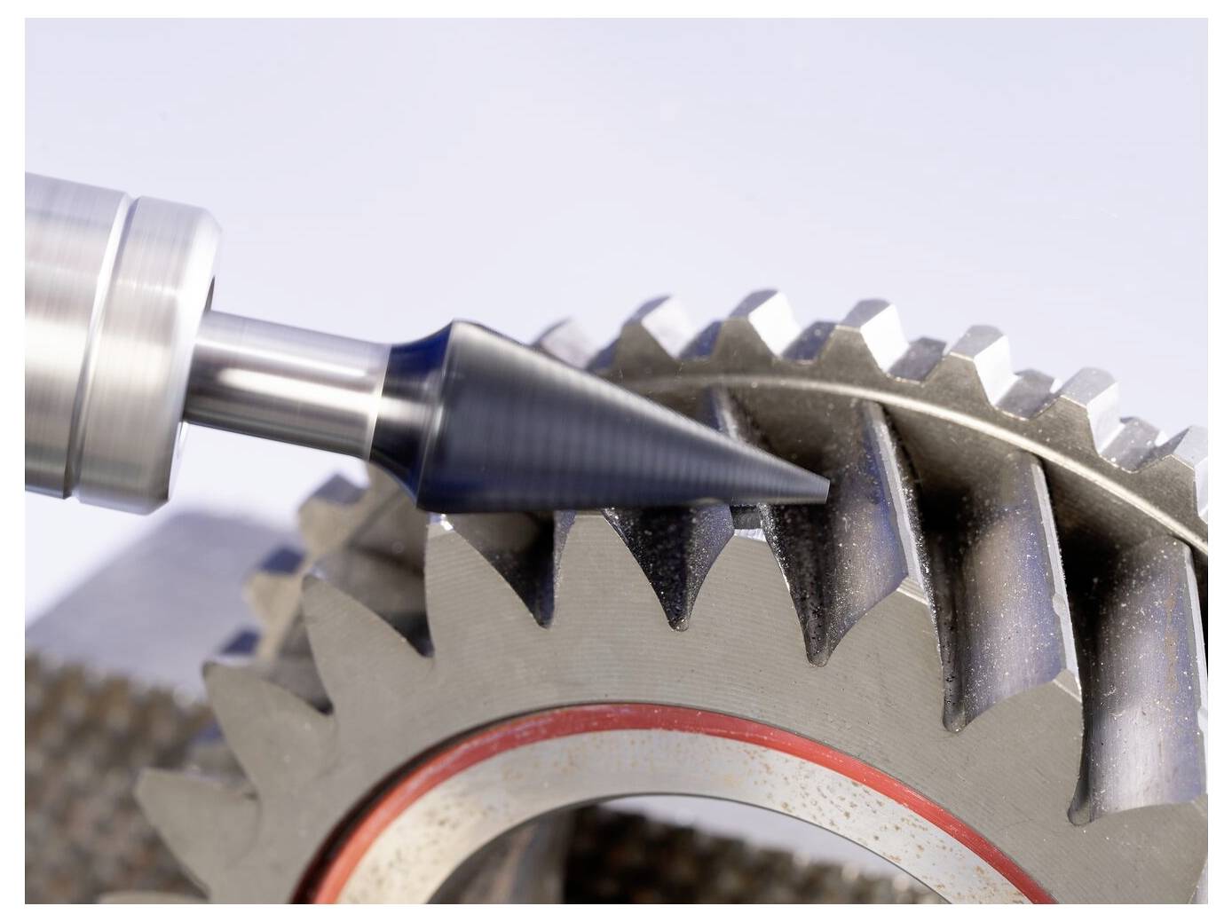 Close-up of a metal machining tool cutting the teeth of a gear, showing precision manufacturing work.