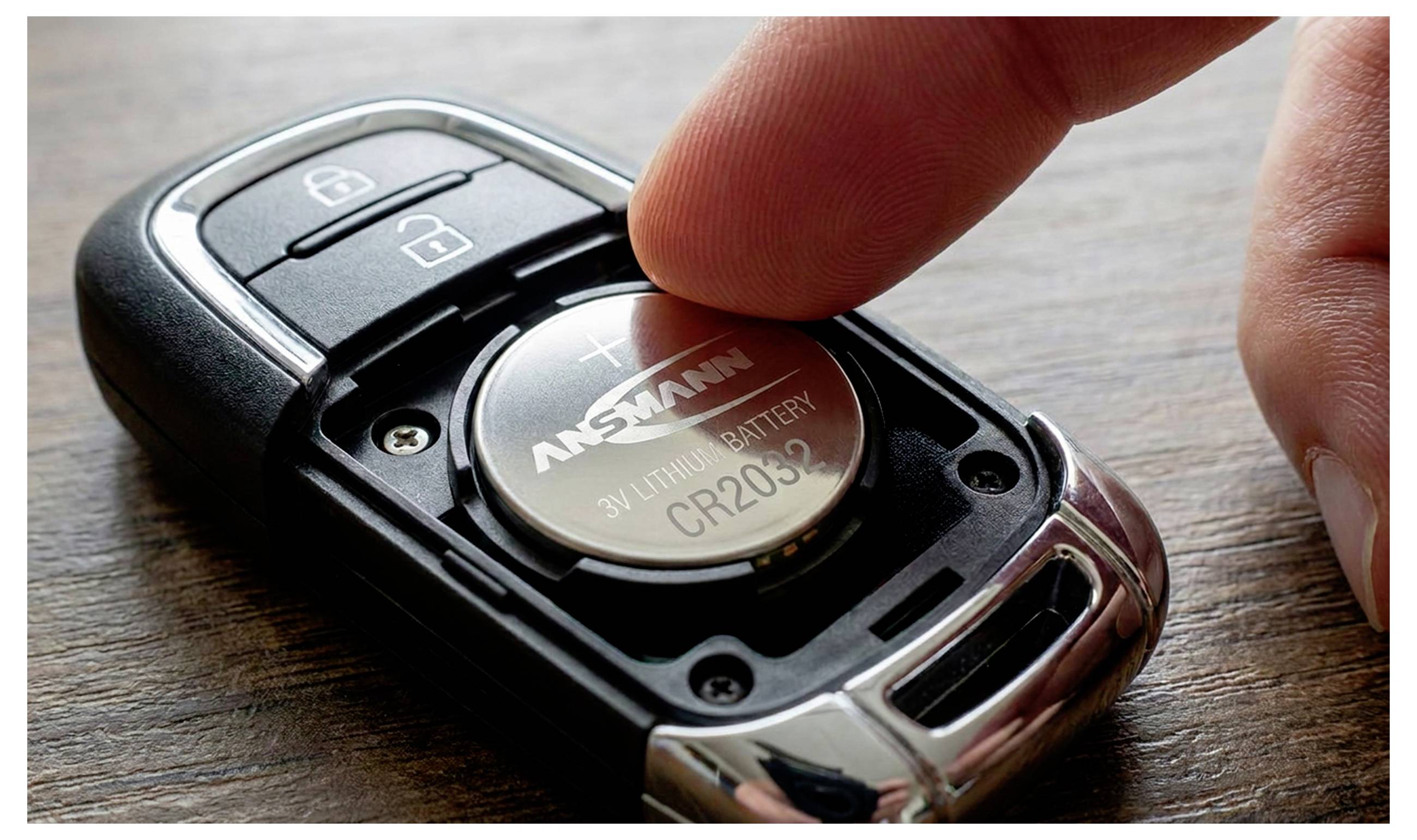 Close-up of a car key fob with a finger pressing the CR2032 battery inside, showing the battery compartment and lock/unlock buttons.