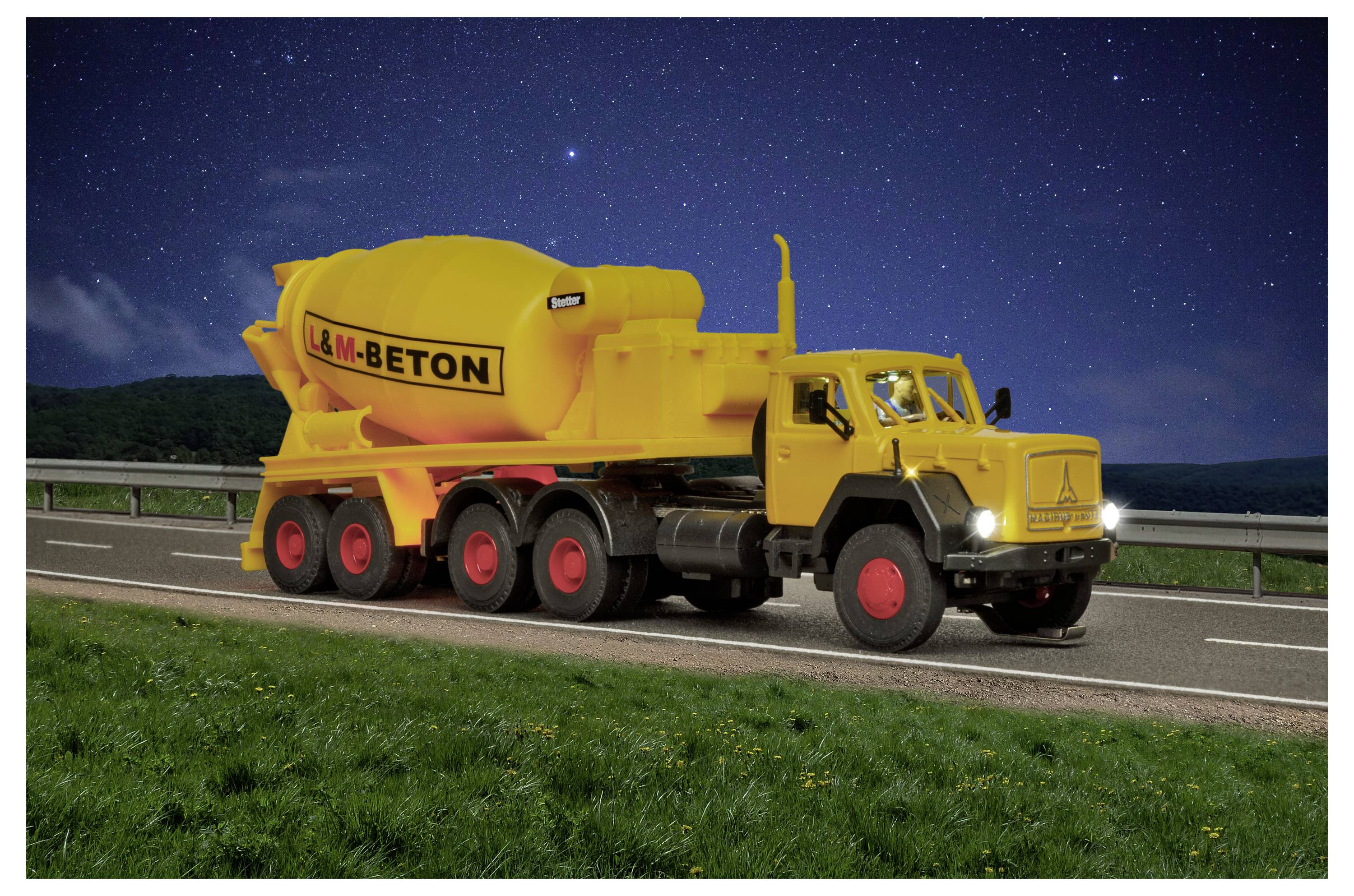 Yellow L&M-Beton concrete mixer truck parked on a roadside at night under a starry sky, with headlights on.