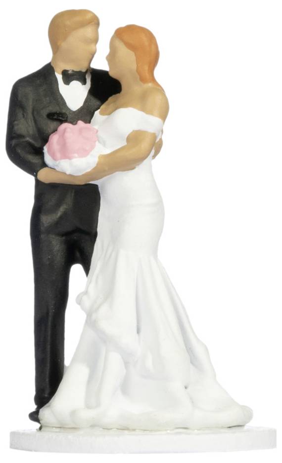 Wedding cake topper figurine of a bride and groom embracing, the bride in a white gown holding pink flowers, the groom in a black tuxedo.