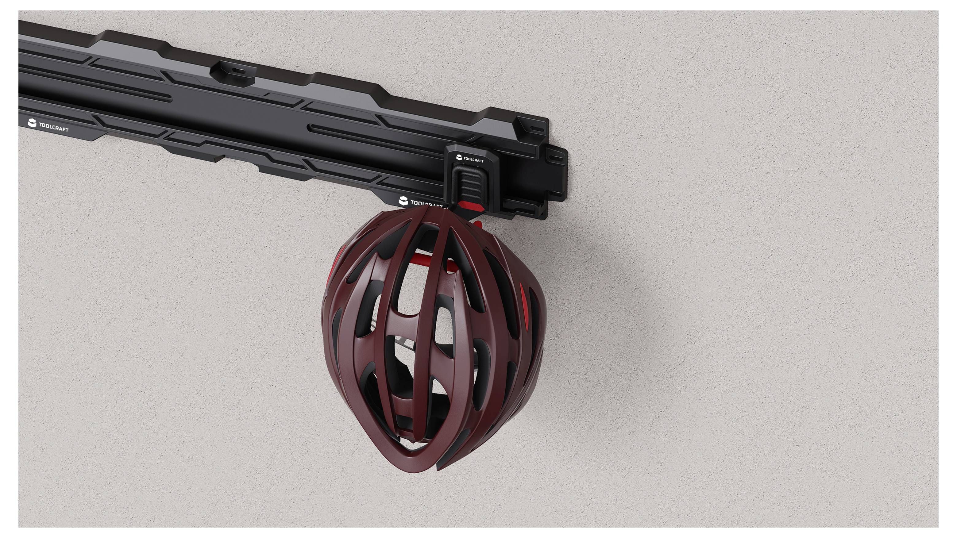 A red bicycle helmet hangs from a wall-mounted black rack beneath a horizontal bike rail.