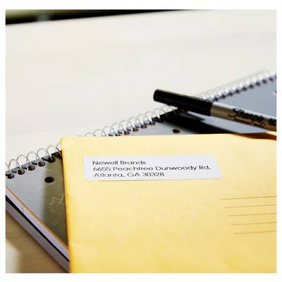 Yellow envelope on a spiral notebook with a mailing label addressed to 'Newell Brands, 6655 Peachtree Dunwoody Rd., Atlanta, GA 30328' and a marker.<br>