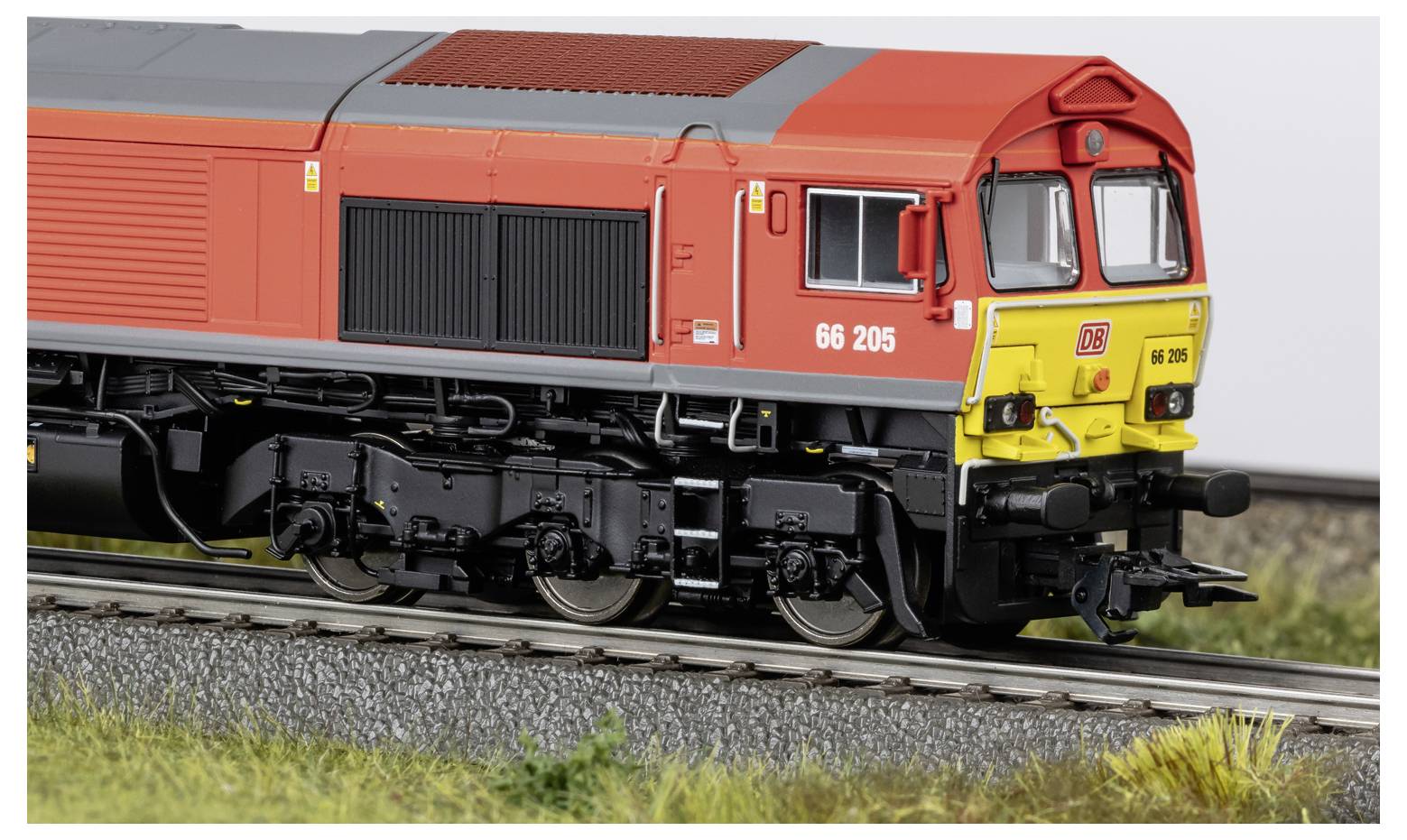 Red and yellow diesel locomotive model on railroad tracks, shown in side view outdoors.
