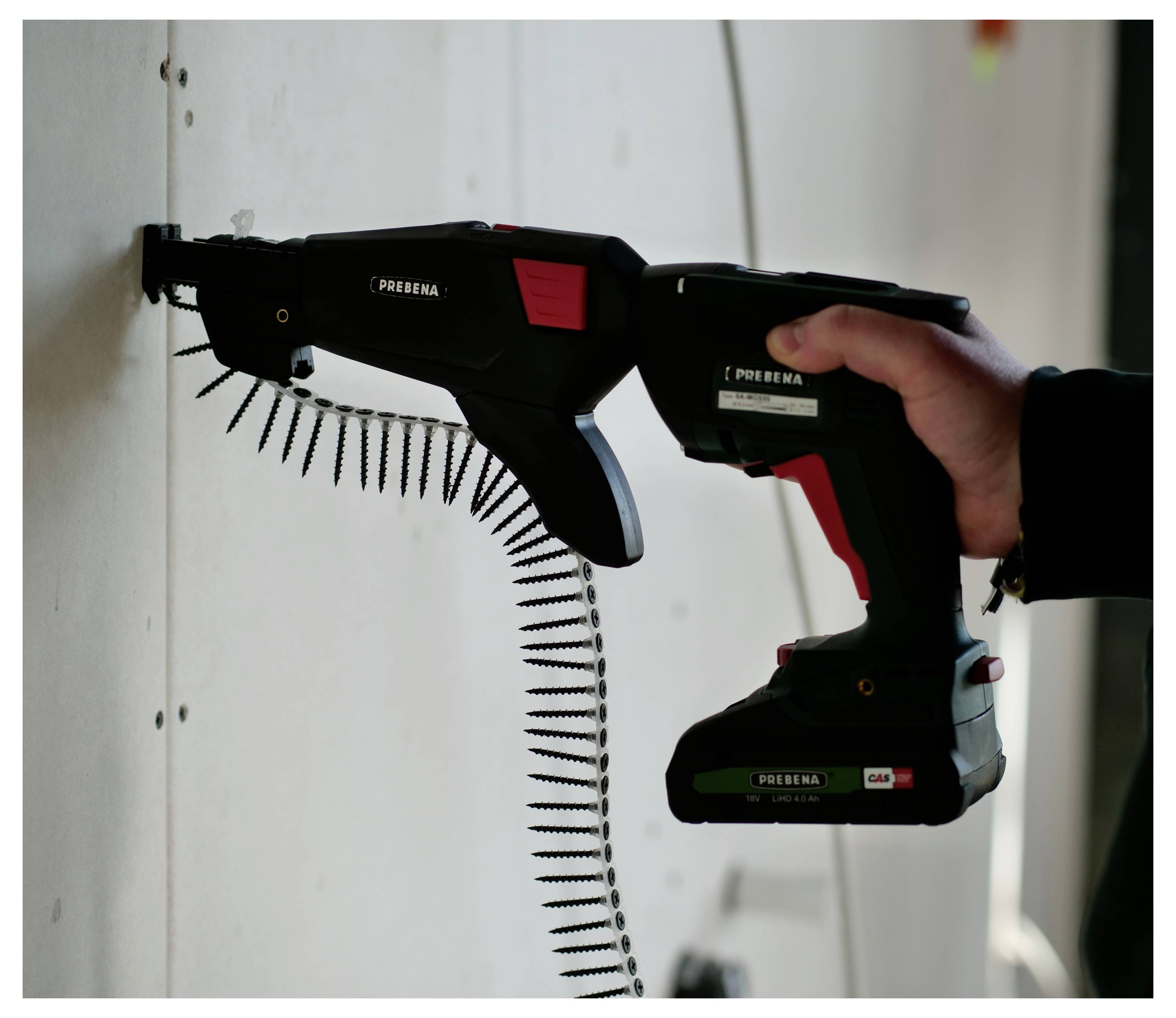Hand holding a cordless screw gun driving a long strip of screws into a wall<br>