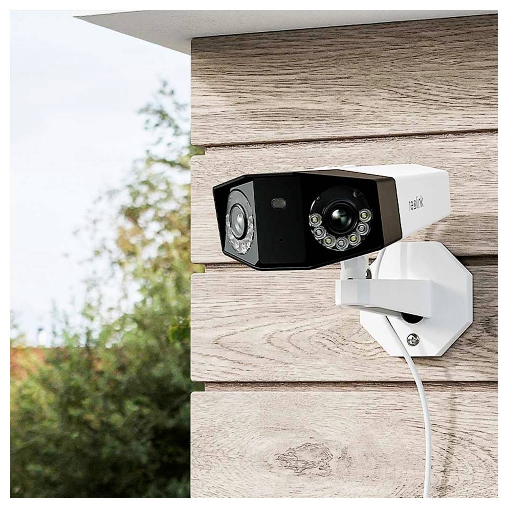 Outdoor Reolink security camera mounted on a house wall, aimed outside with a visible power cable.