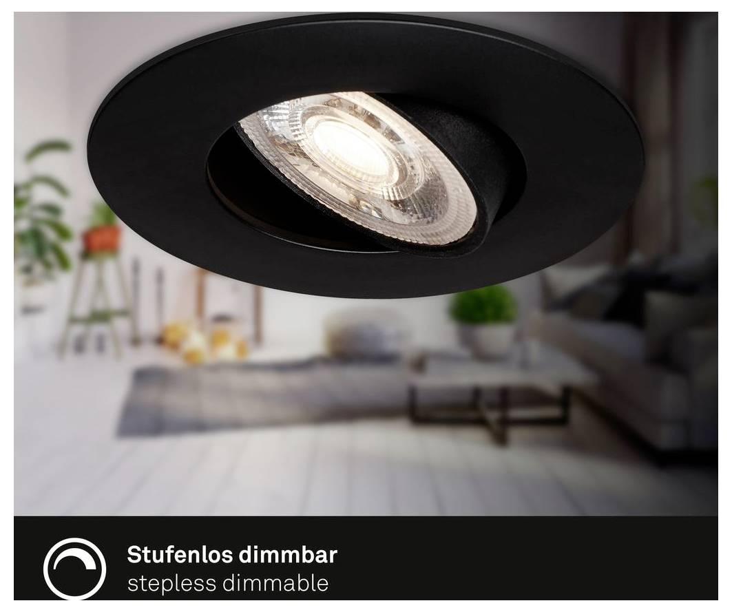 Close-up of a black recessed ceiling spotlight, labeled 'Stufenlos dimmbar' and 'Stepless dimmable,' with a blurred living room background.