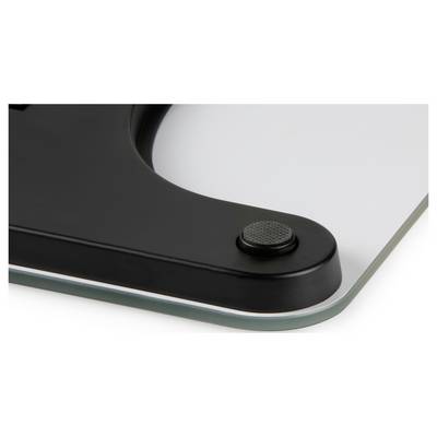 Close-up of a black device corner with a textured round button mounted on a glass surface.<br>
