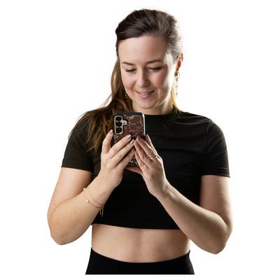 Young woman in a black top smiling while looking down at her smartphone against a white background.