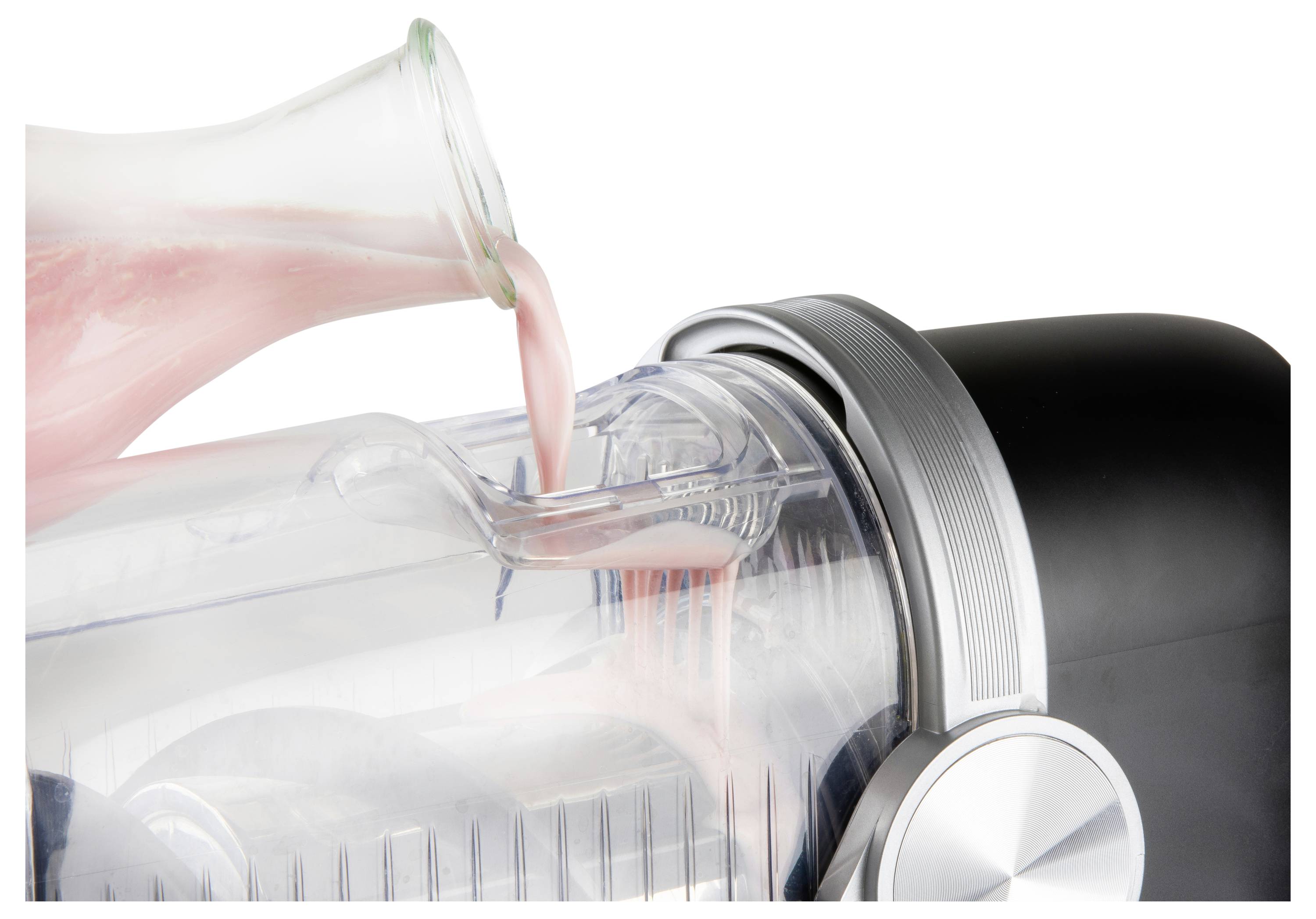 Red liquid is being poured from a container into a clear electric blender pitcher.