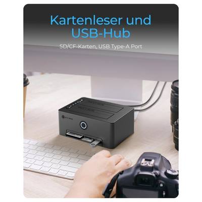Desktop card reader and USB hub with SD/CF slots and a USB Type-A port, shown beside a keyboard and camera on a desk.