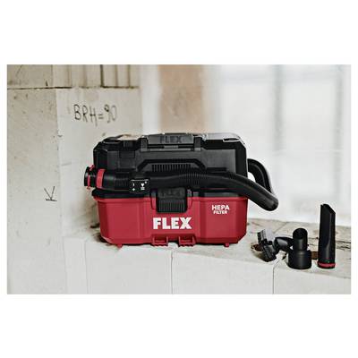 Red FLEX HEPA wet/dry vacuum on a concrete ledge with hose and attachments beside it, shown in a construction setting.