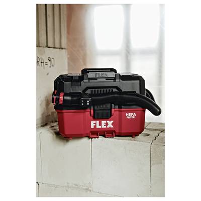 Red-and-black FLEX HEPA filter vacuum, shown on a concrete block in a workshop or construction setting.