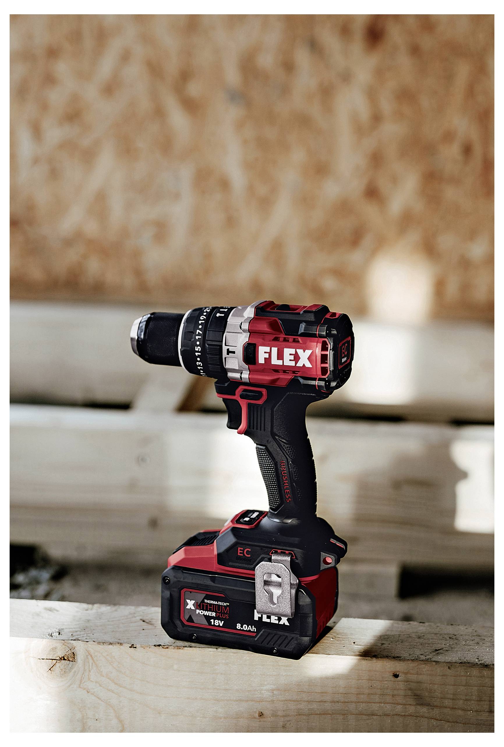 Cordless FLEX drill standing upright on a wooden surface, black and red with battery attached and visible 'FLEX' branding.