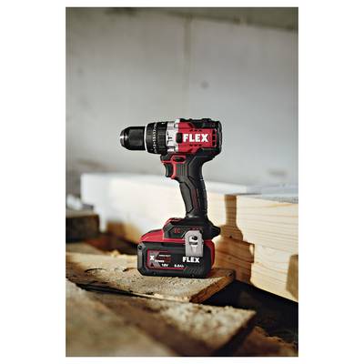 Red and black FLEX cordless drill standing on a wooden workbench beside stacked lumber in a workshop.