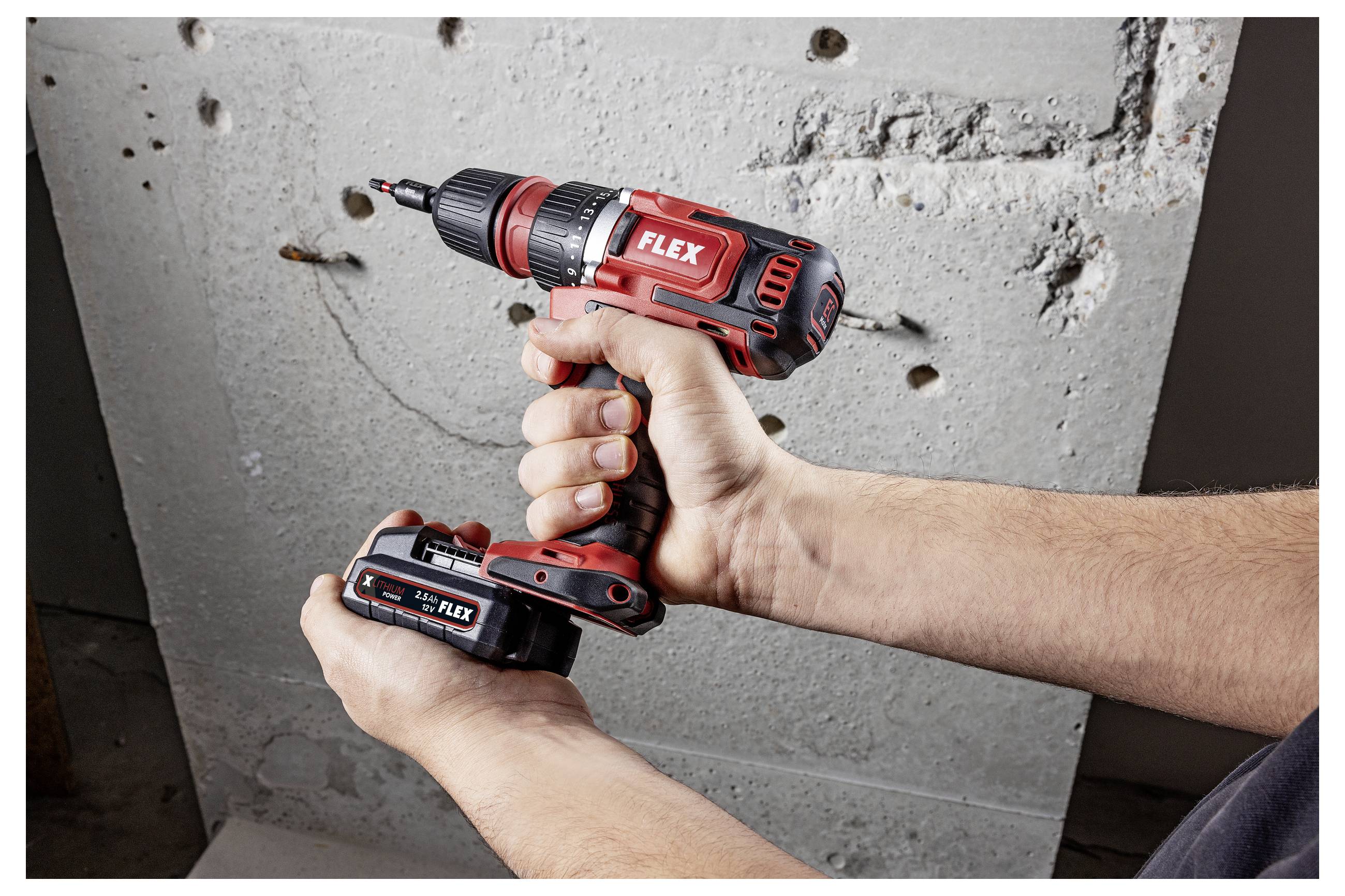 Hands holding a FLEX cordless drill driver drilling into a concrete wall with exposed holes and rough surface.
