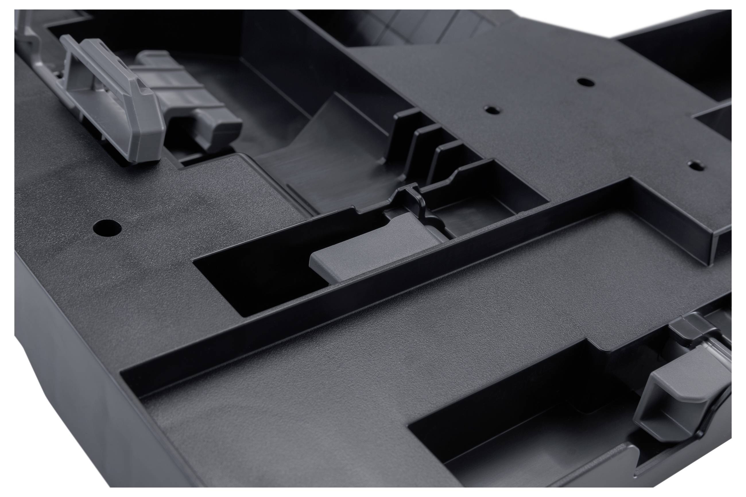 Close-up of a black molded plastic tray with compartments and clips, likely packaging or a device insert.