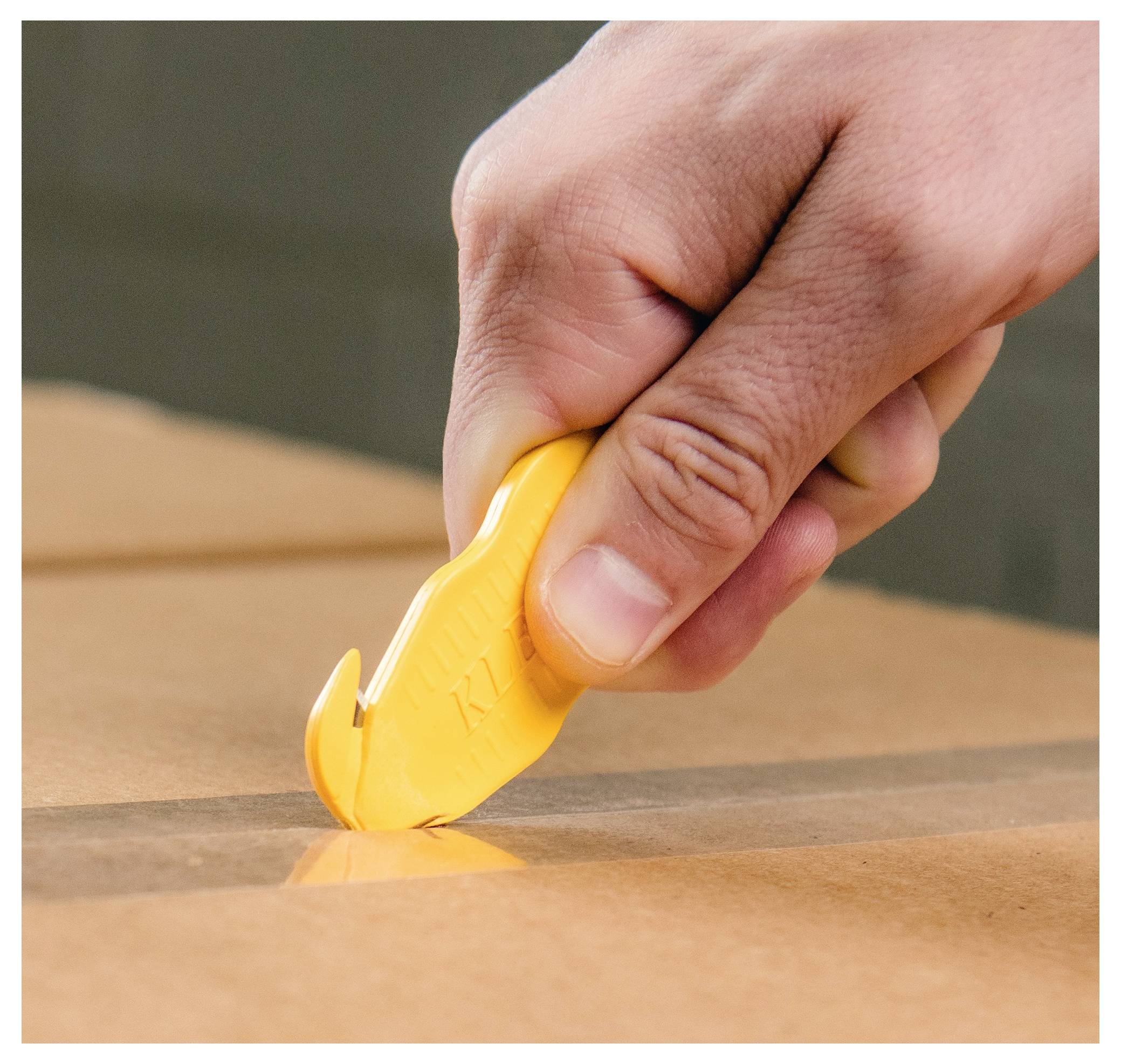 Hand using a yellow utility knife to cut packing tape on a cardboard box.<br>