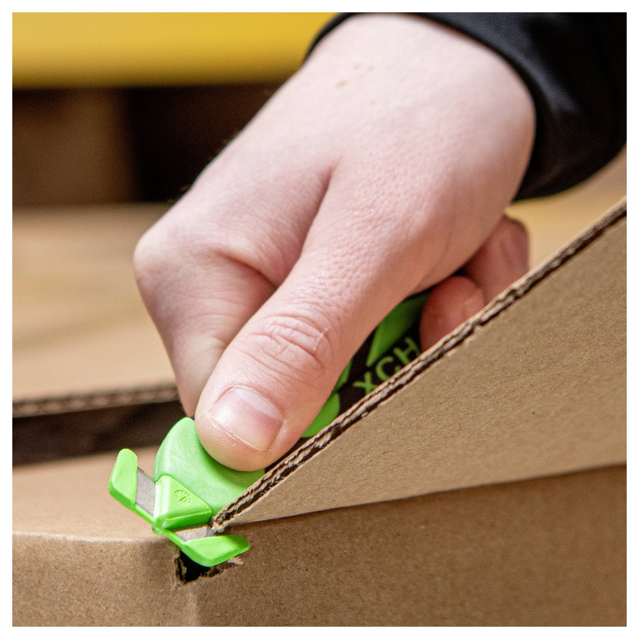 Close-up of a hand using a green utility cutter to open a cardboard box along the taped seam.