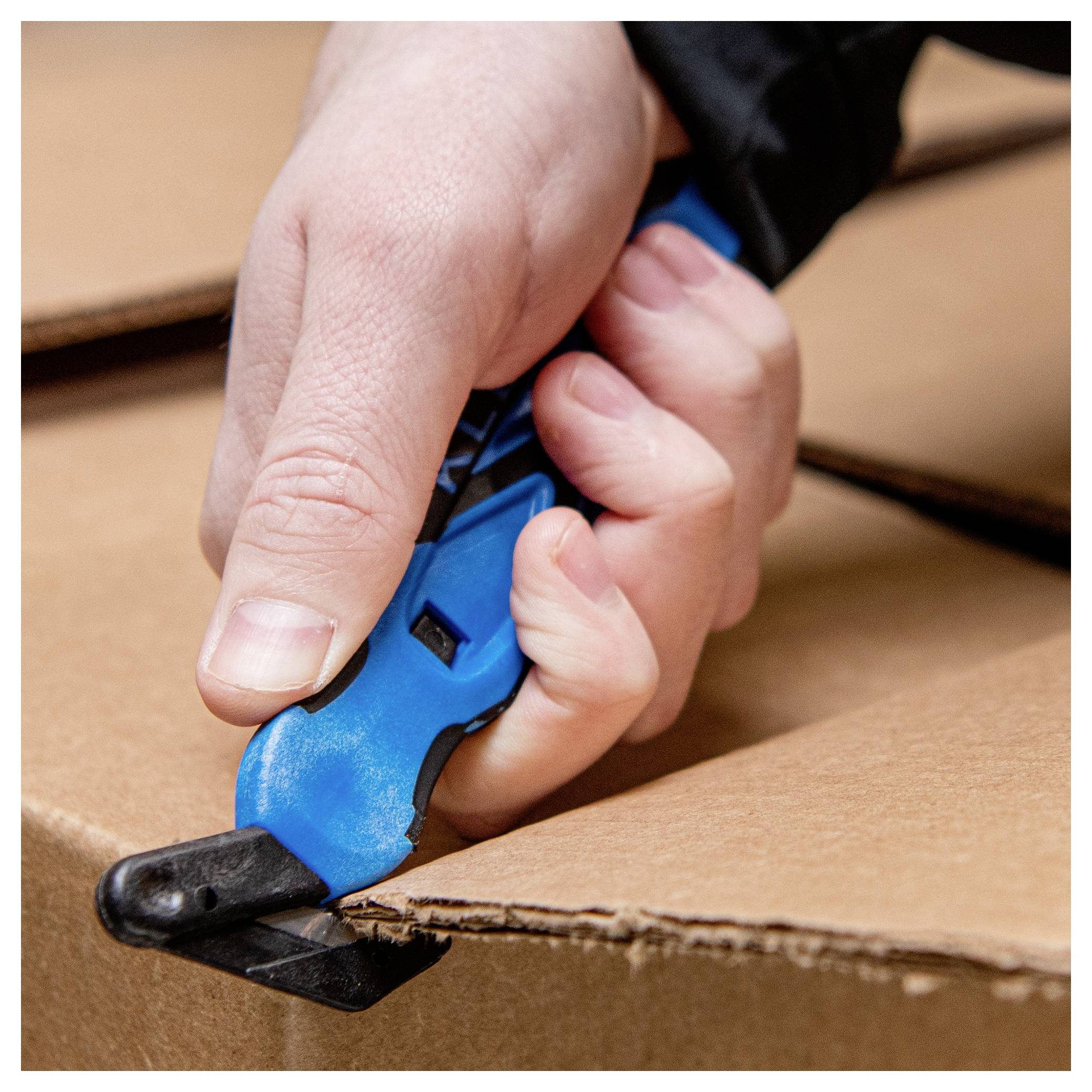 Close-up of a hand using a blue utility knife to cut open a cardboard box.