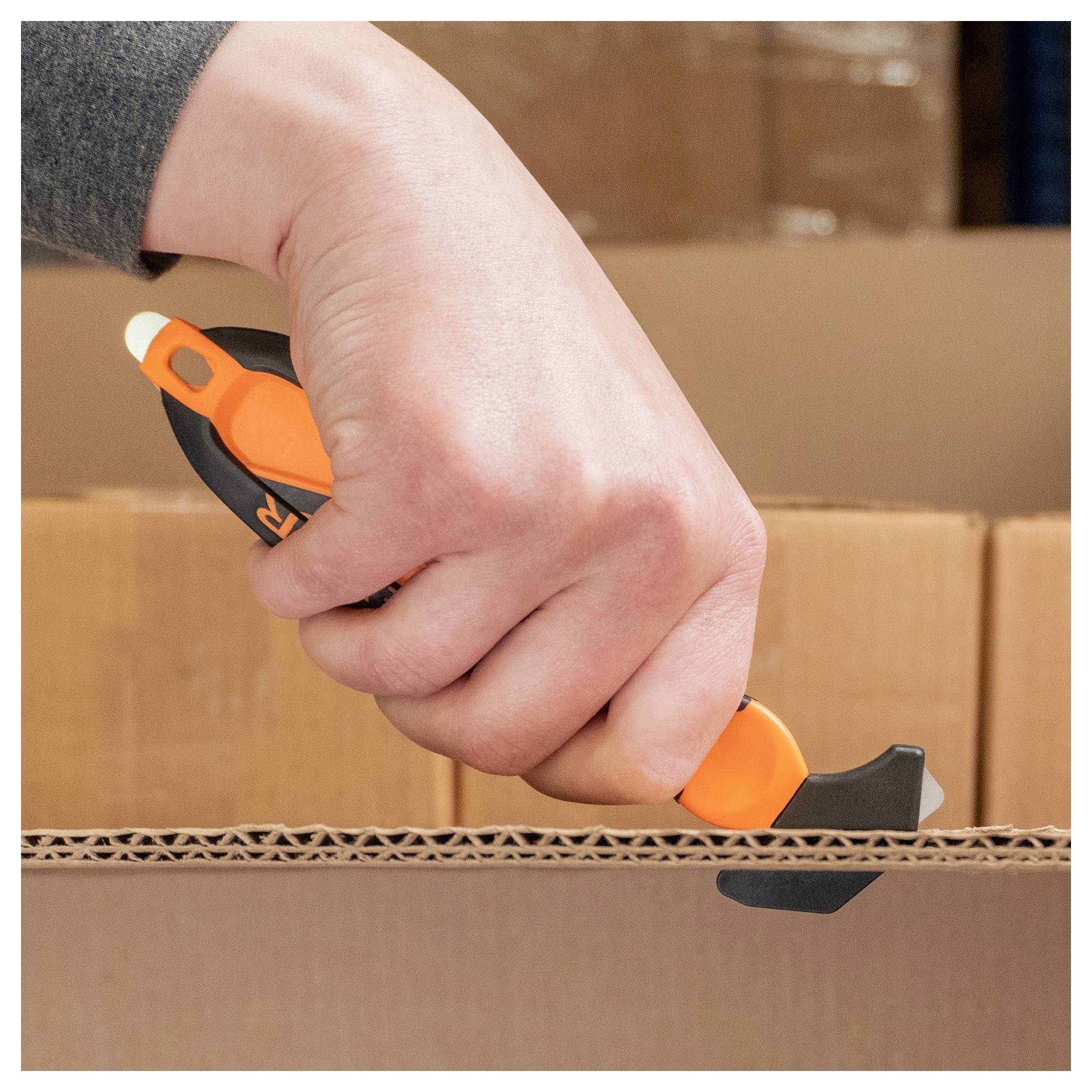 Hand using a box cutter to open a cardboard shipping box.<br>
