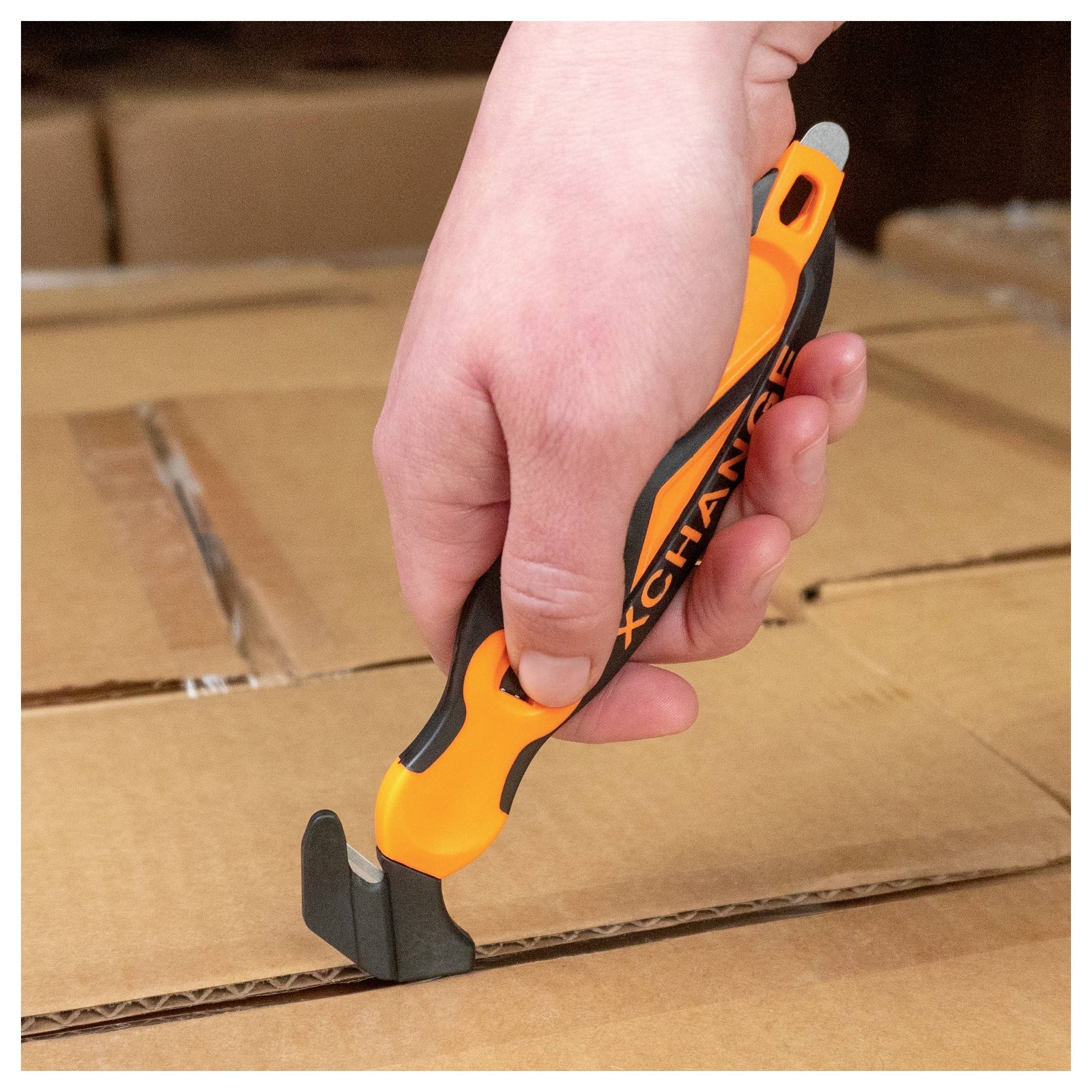 Close-up of a hand using a box cutter to open a sealed cardboard shipping box.