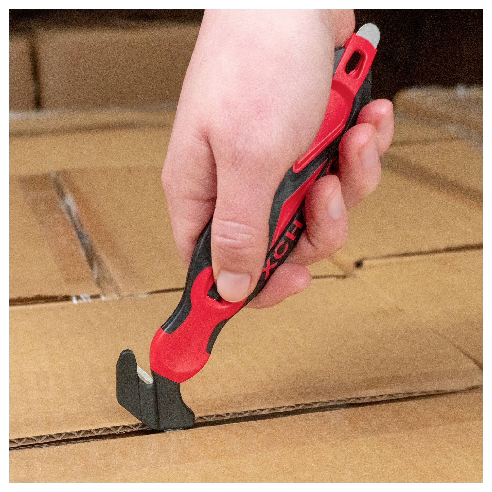 Hand using a red and black box cutter to slice open a cardboard shipping box.<br>