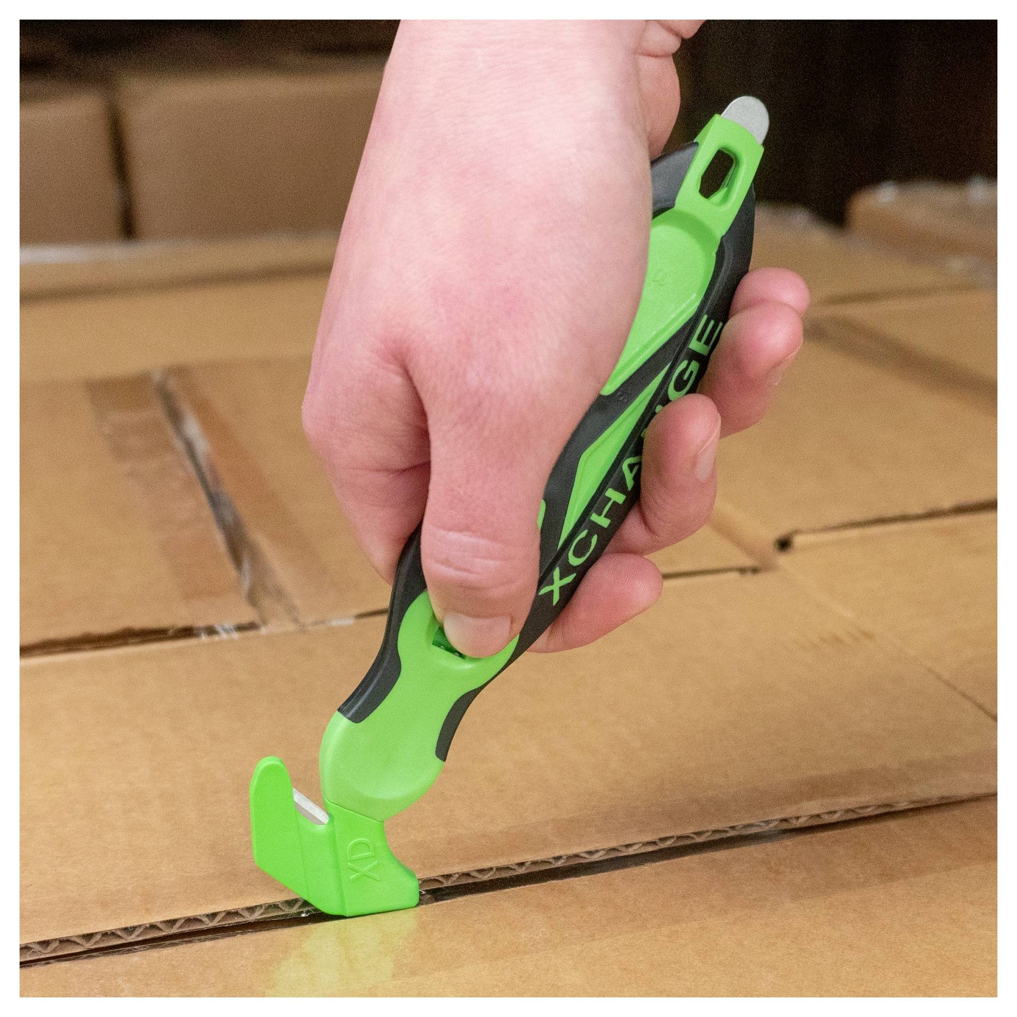 A hand uses a green box cutter to open a cardboard shipping box.<br>