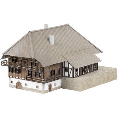 Architectural model of a traditional chalet-style house with steep tiled roof, wooden upper floors, and stone lower walls.