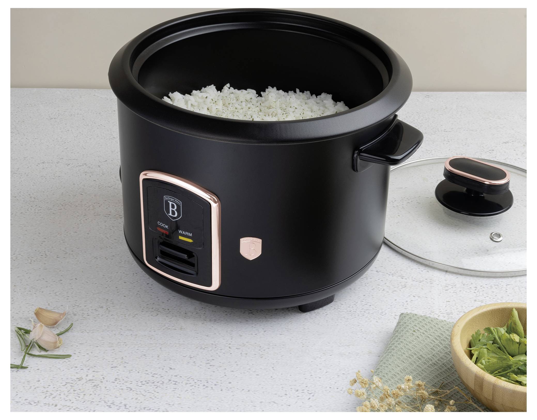 Black electric rice cooker with open lid, filled with cooked rice, on a countertop with its lid beside it.<br>