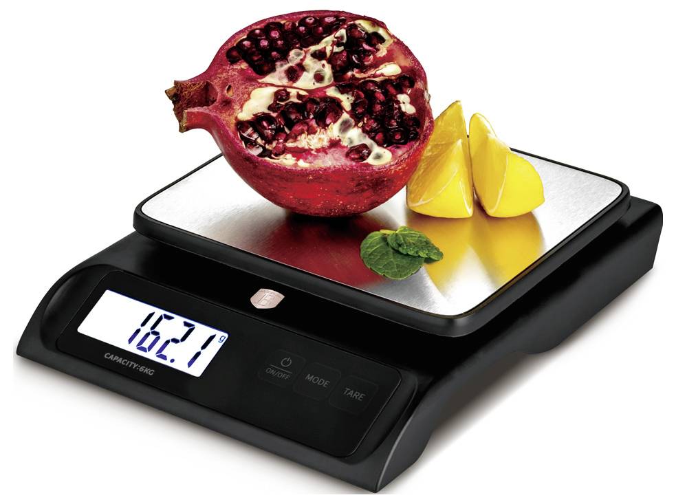 Digital kitchen scale displaying 162.7 with a cut-open pomegranate and orange slices on the weighing platform.