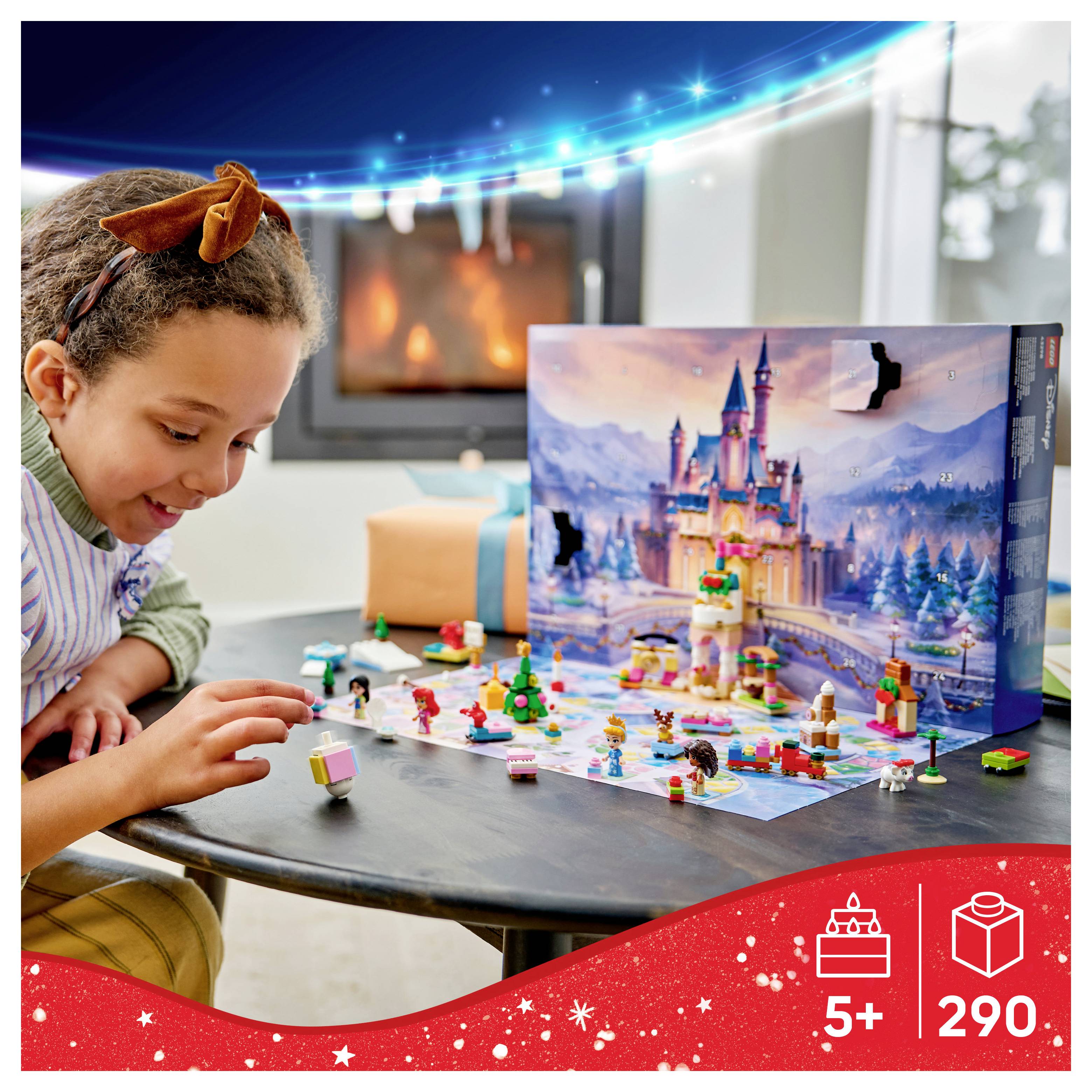 Young girl plays with a 290-piece castle-themed building set on a table; '5+' age label is shown on the box.