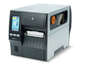 Industrial desktop label printer with touchscreen display, front label output slot, and visible media roll inside the side compartment.