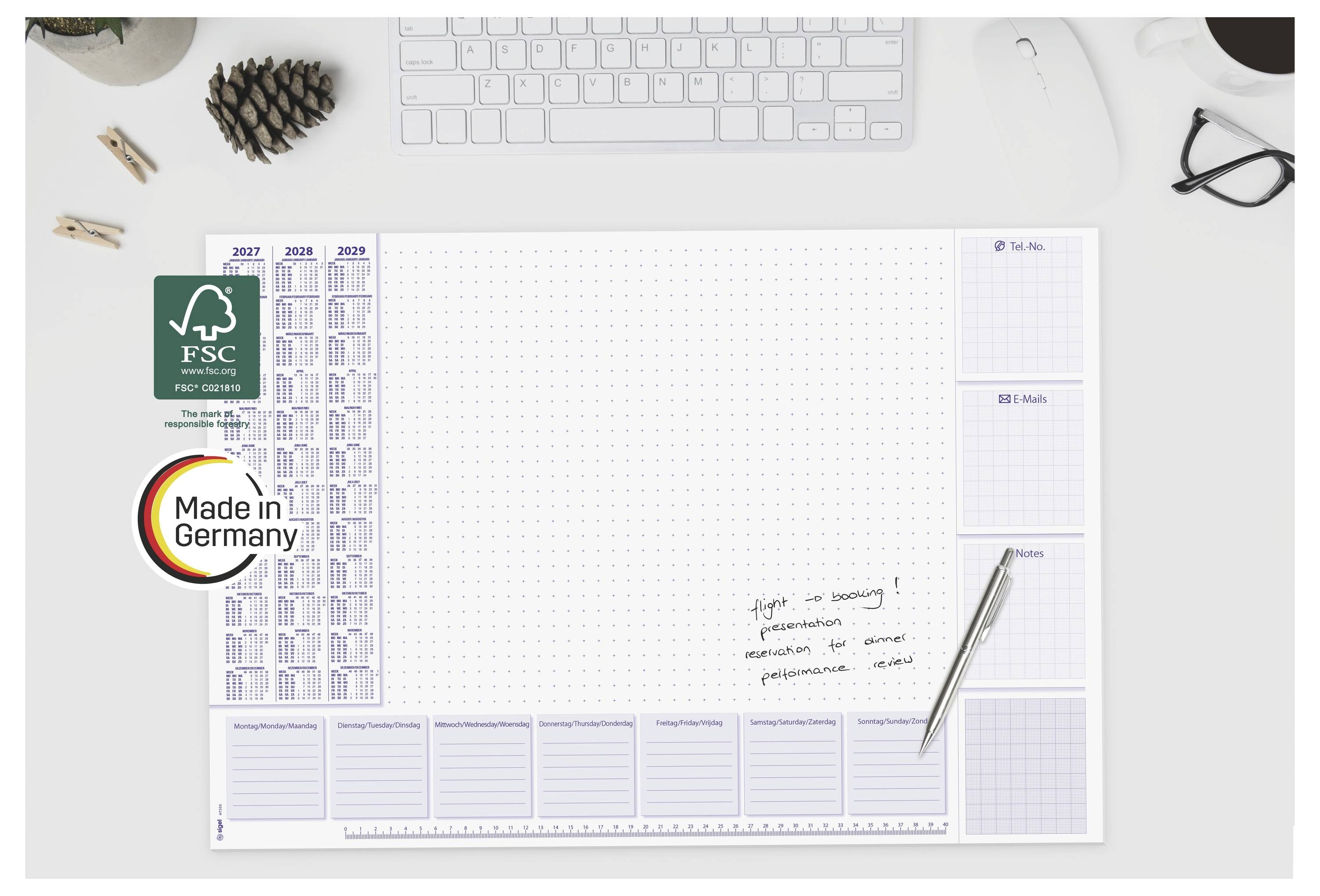 Desk flat lay of an undated planner page with mini yearly calendars, notes sections, pen, and 'FSC' and 'Made in Germany' labels.