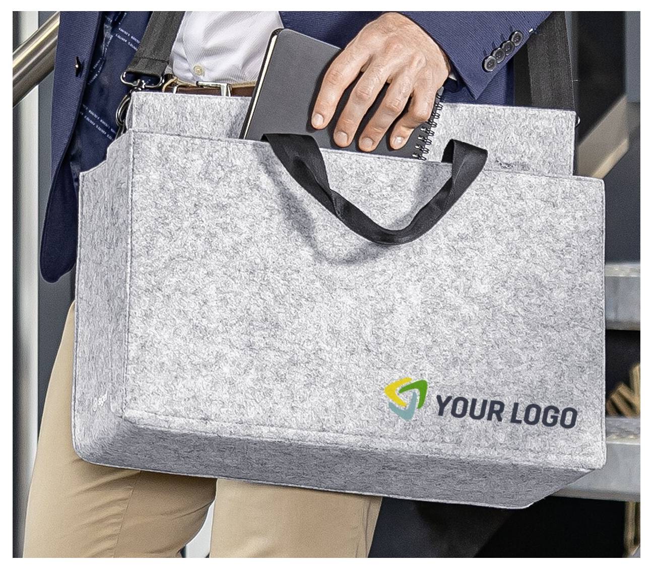 Person holding a gray felt laptop bag with black handles and a 'YOUR LOGO' placeholder printed on the front.