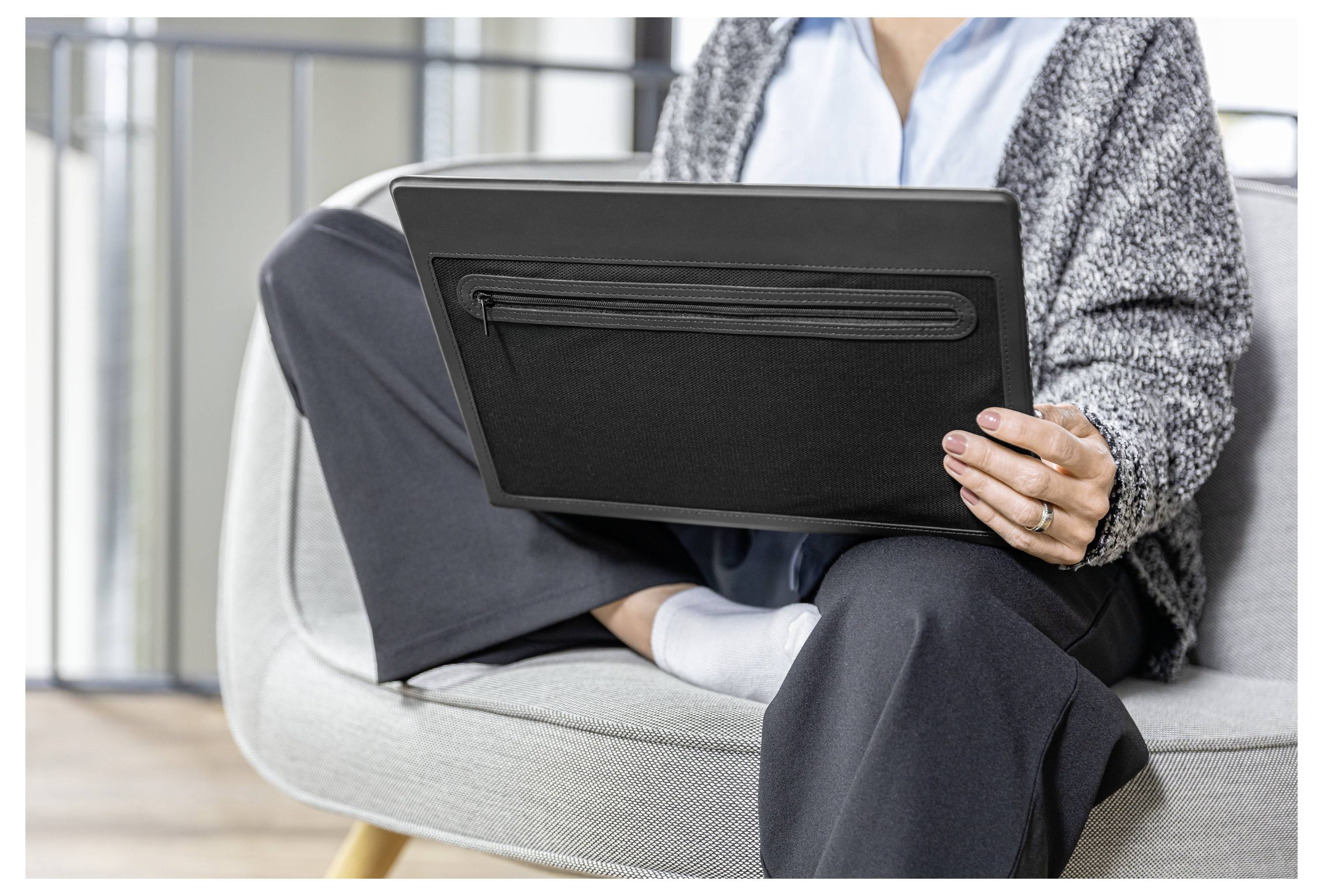 Person seated in a chair using a laptop, with legs crossed in a casual indoor setting.