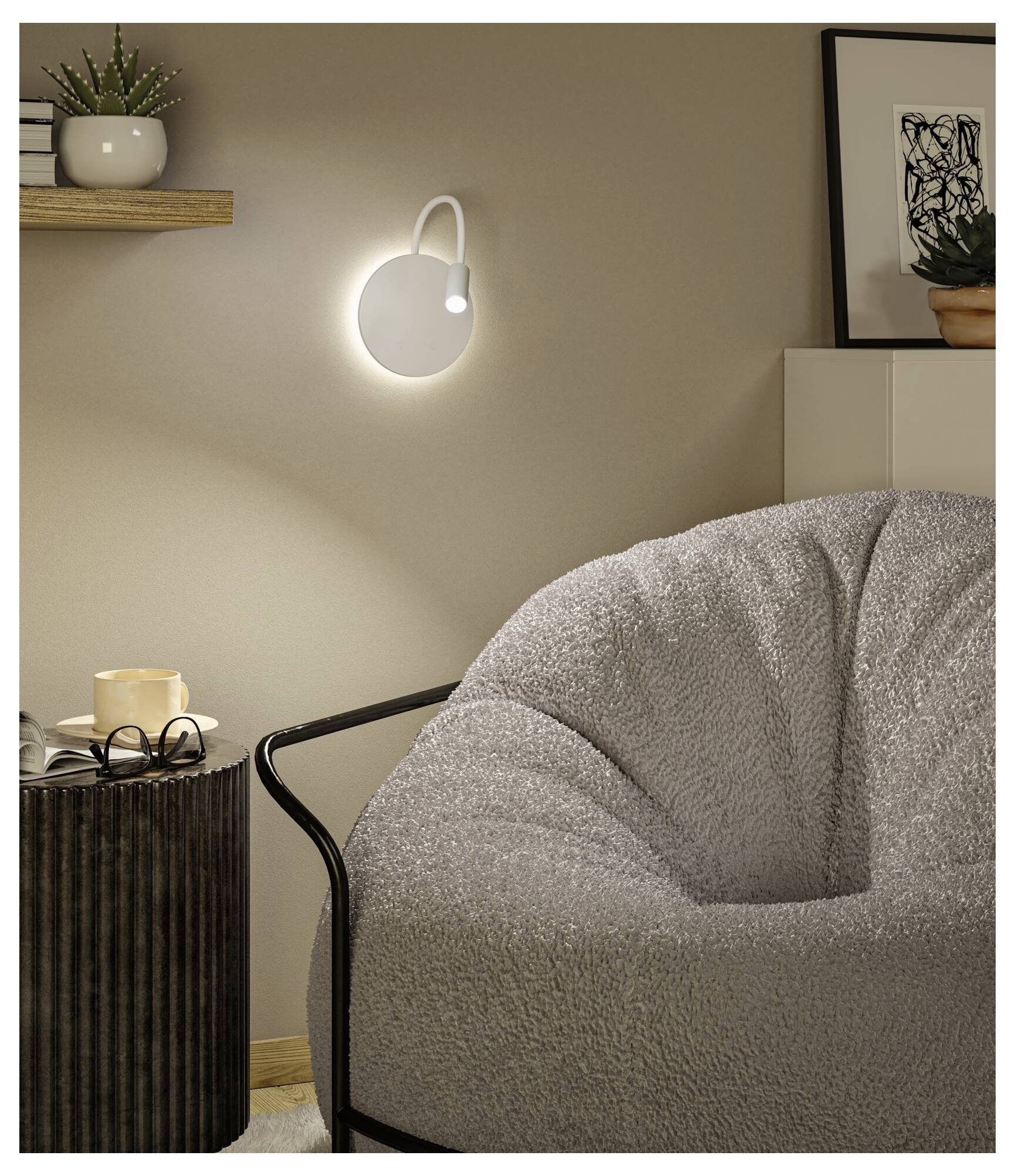 A glowing wall-mounted light illuminates a cozy corner with a gray cushioned chair, side table, shelf plant, and framed art.<br>