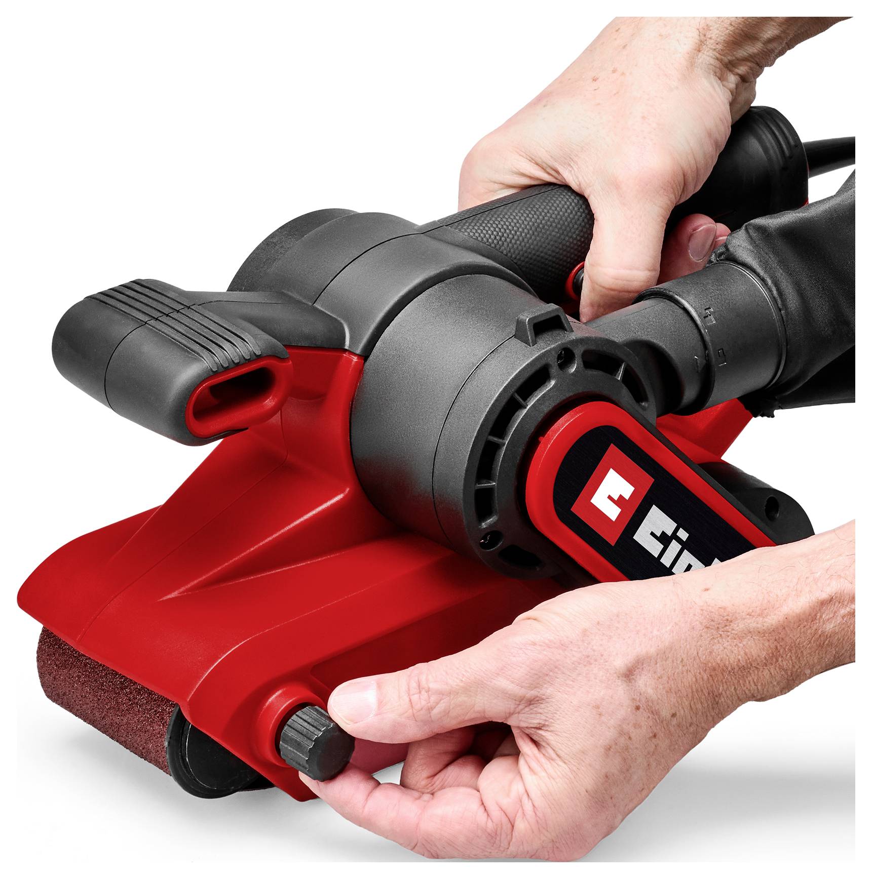 Hands adjusting a red handheld electric sander on a white background, showing the front knob and control area being held in place.
