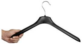 A hand holding a black clothes hanger on a white background.