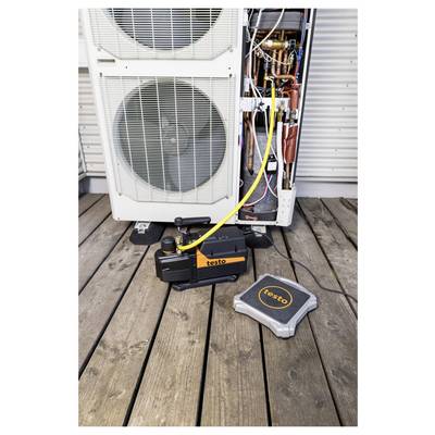 Outdoor HVAC unit with open service panel connected to a yellow test hose and diagnostic equipment on a wooden deck.