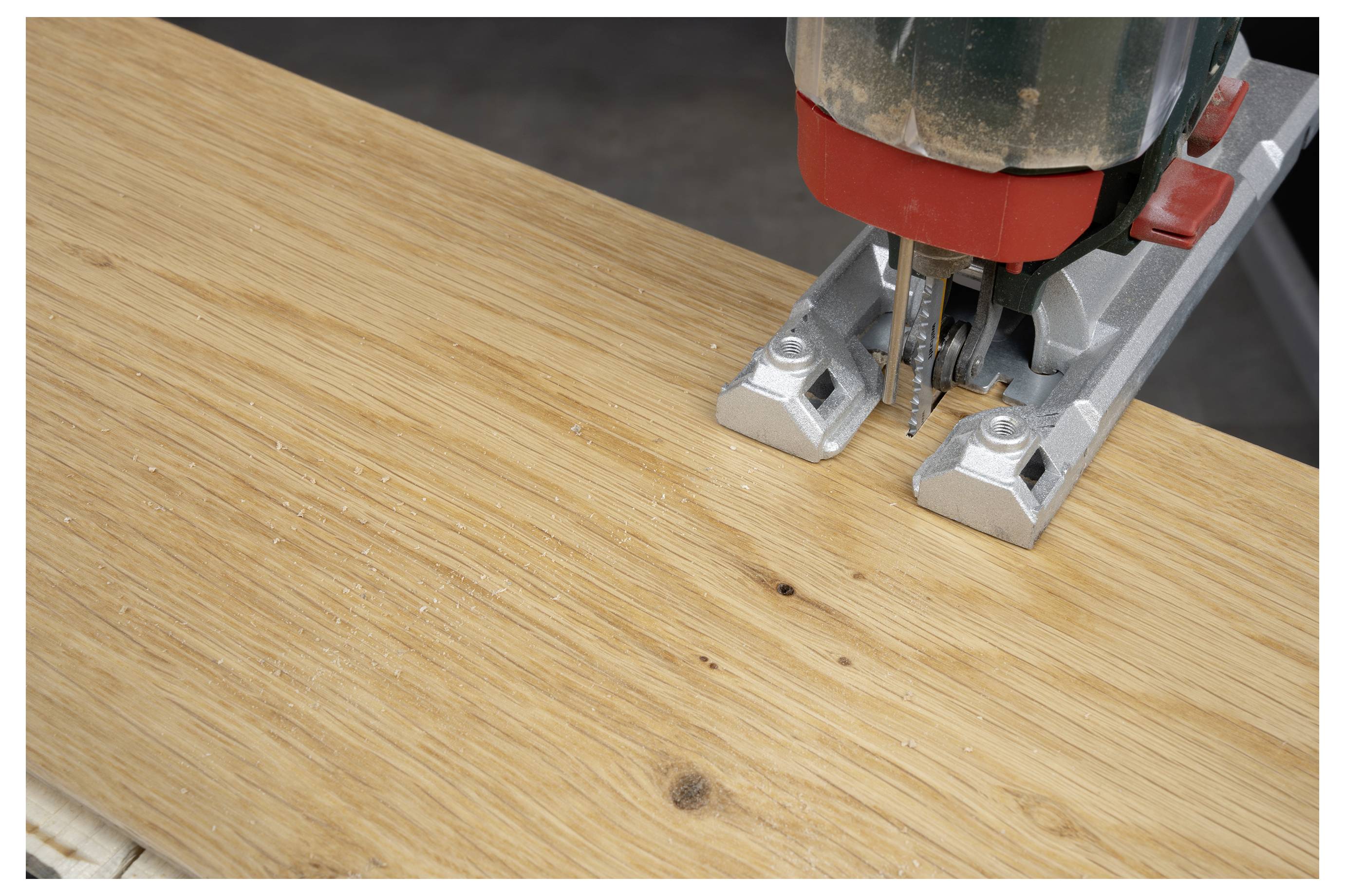 Jigsaw cutting a hole in a wooden board on a workbench.