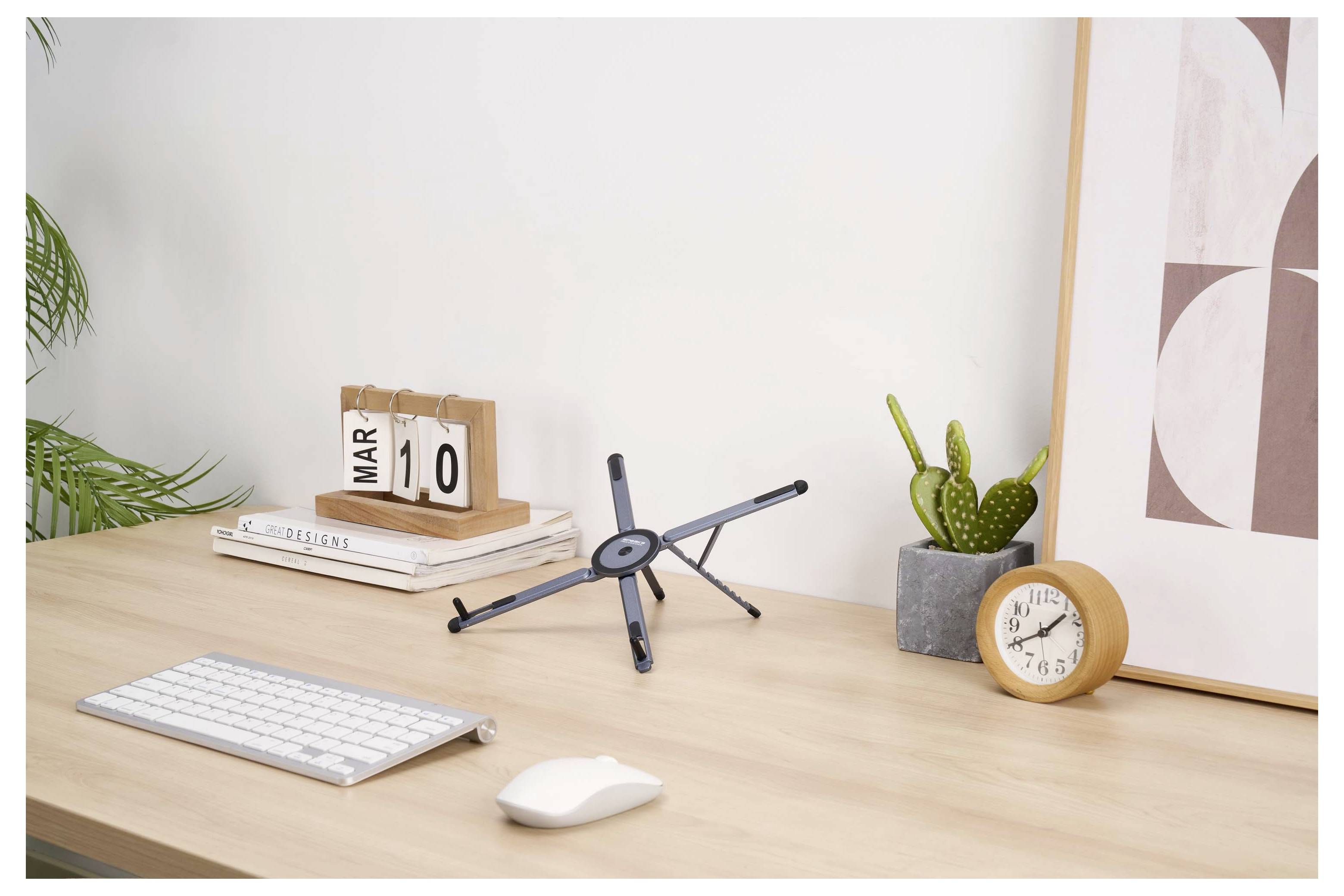 Minimal desk setup with keyboard, mouse, planner, pen stand, phone holder, clock, and plant in a bright workspace.