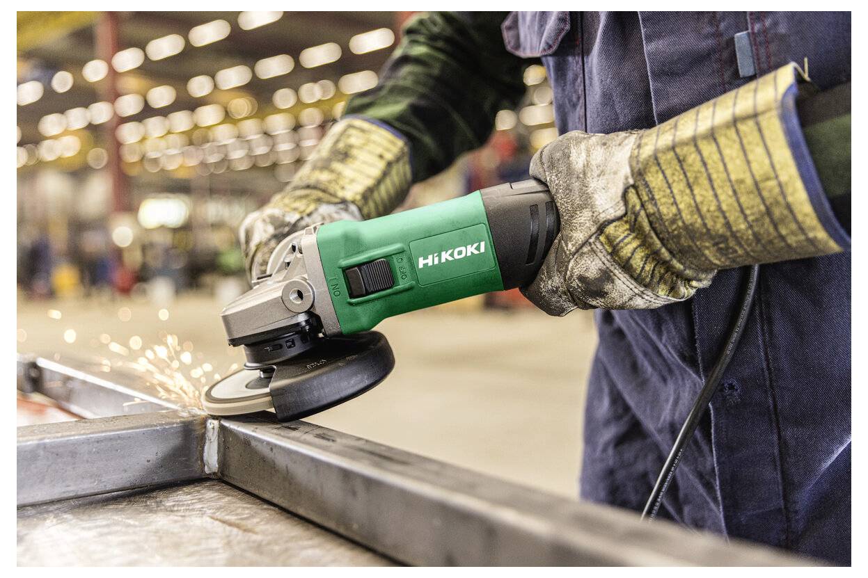 Worker using an angle grinder on a metal piece, producing sparks in a workshop<br>