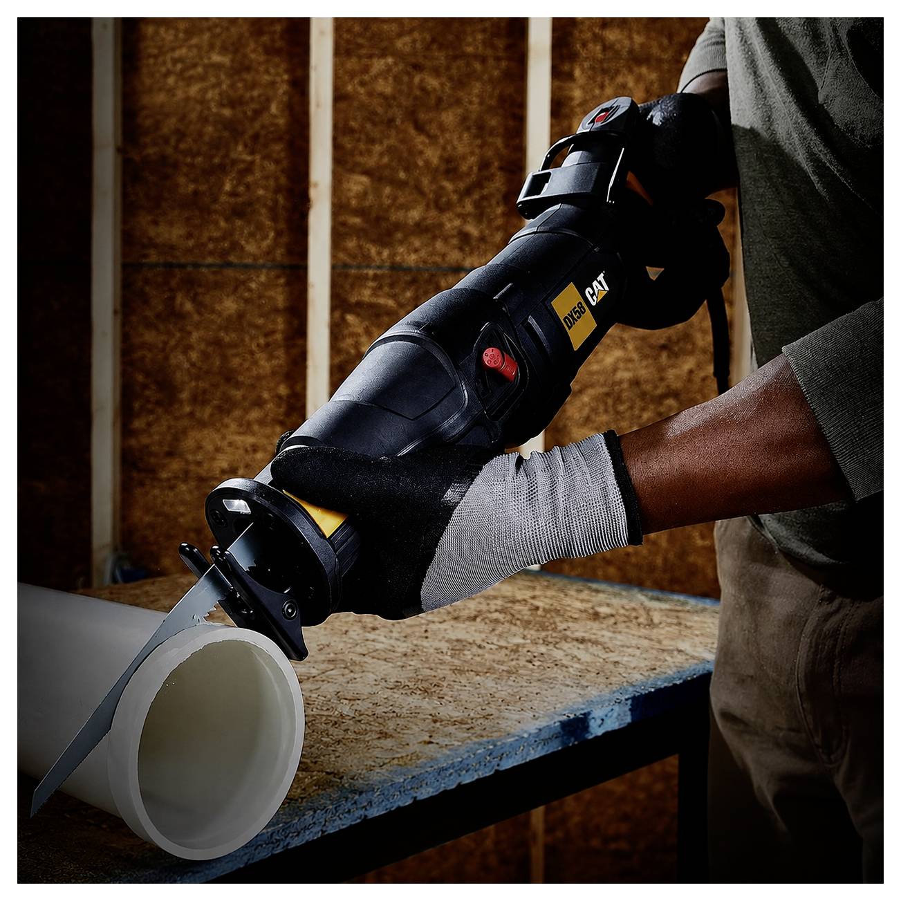 Person using a reciprocating saw to cut a white PVC pipe on a workbench.