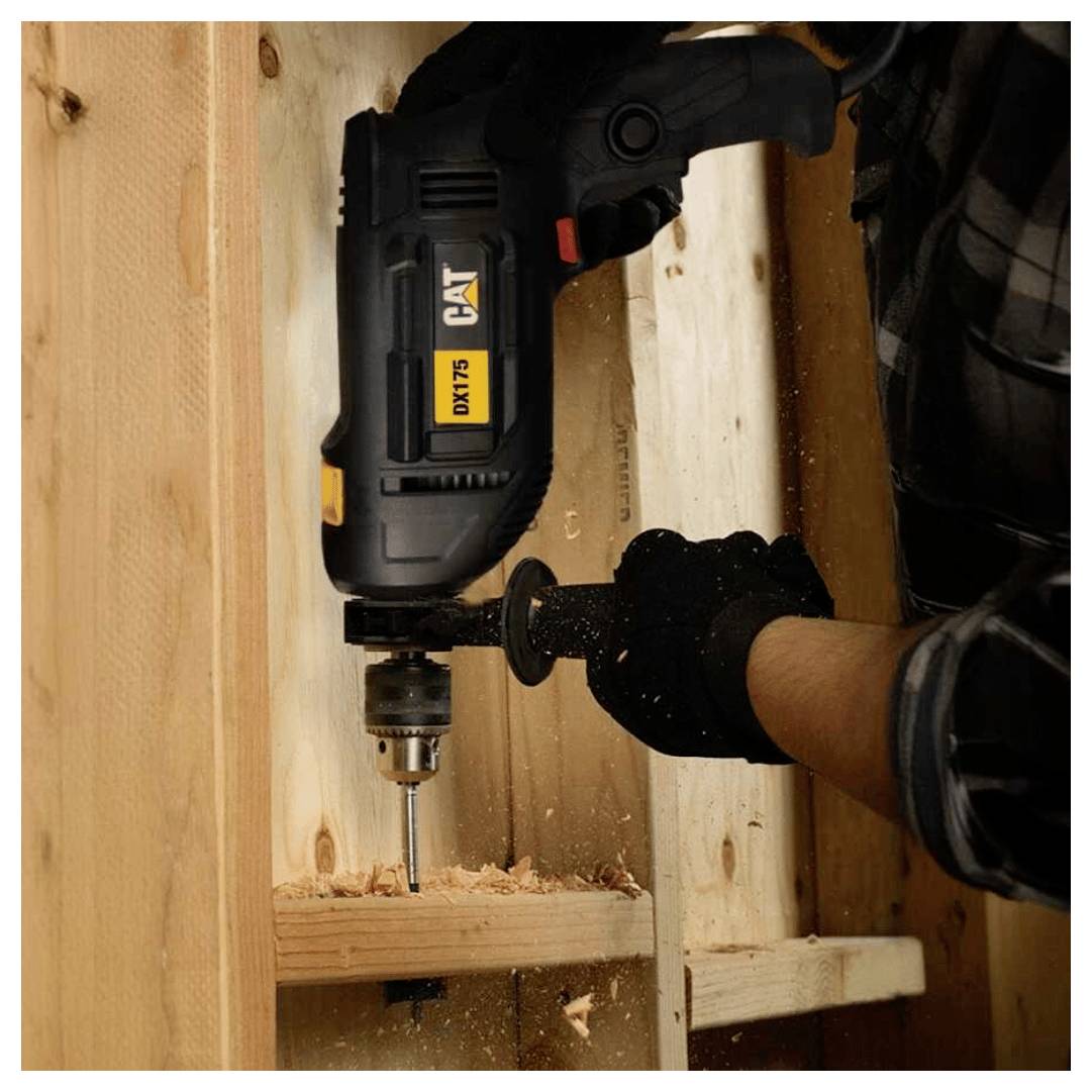 Person using a CAT cordless drill to bore a hole into wooden framing inside a construction area.